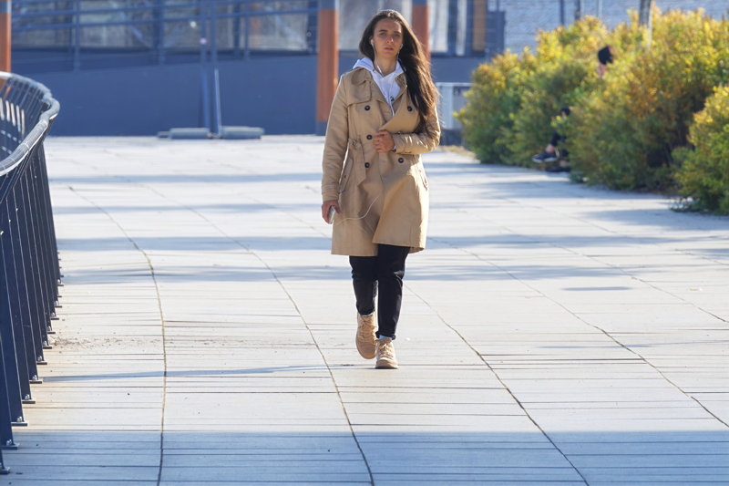 15 - A person wearing a beige Burberry Chelsea Heritage trench coat, walking